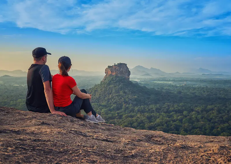 A tourist couple enjoys a breathtaking view of Sigiriya from Pidurangala rock