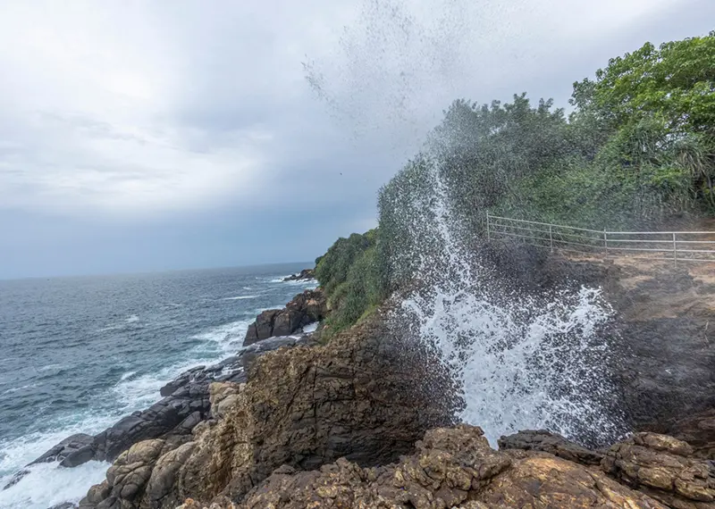Spectacular natural blowhole spraying ocean water high against dramatic rocky coastal cliffs