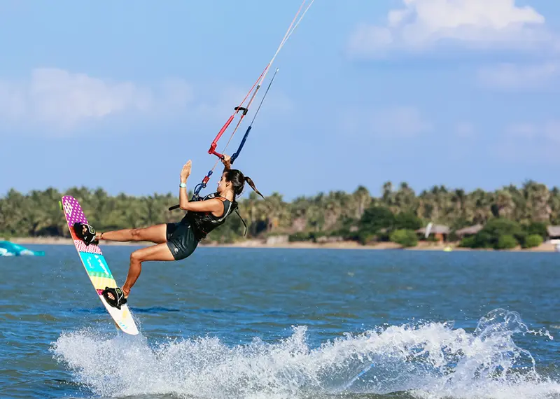 Skilled female kiteboarder jumping high above the water during an active holiday