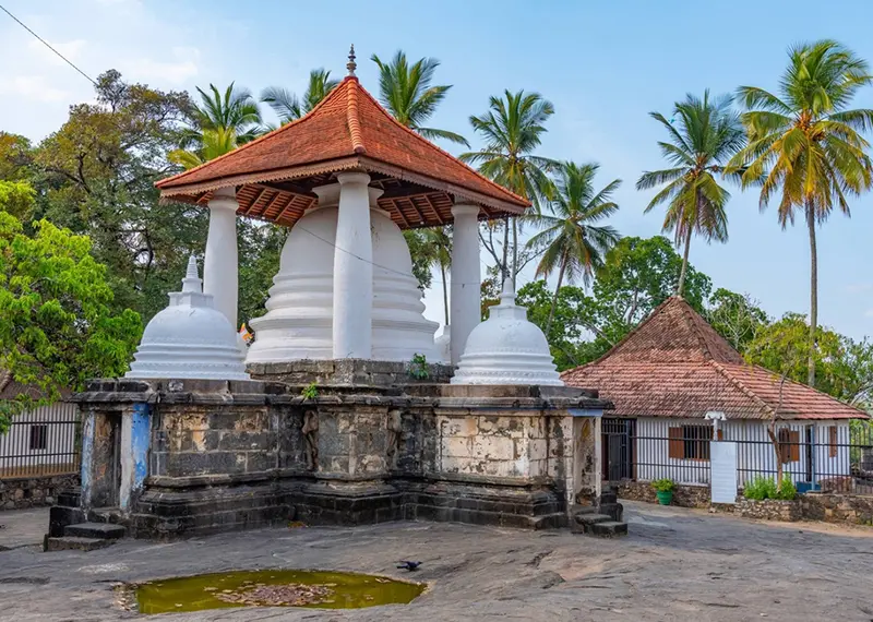 Ancient white-domed Buddhist stupa protected by a traditional red-tiled roof structure