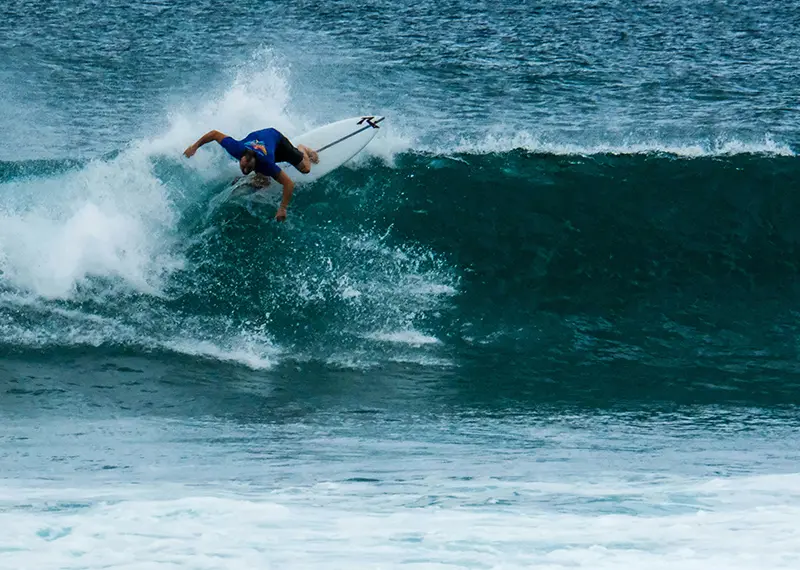 Skilled surfer riding a large green ocean wave during a tropical holiday