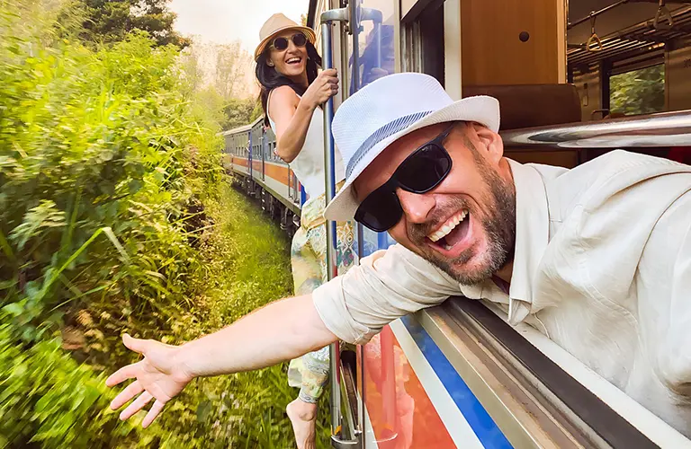 A smiling man and woman leaning out of a moving train window, enjoying the lush green scenery during Enchanting Sri Lanka - A 17 Day Bespoke Honeymoon Odyssey tour