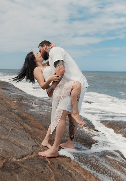 A romantic couple dressed in white kissing on rocky coastal shorelines, representing the intimate and scenic experiences offered by our honeymoon Sri Lanka tours