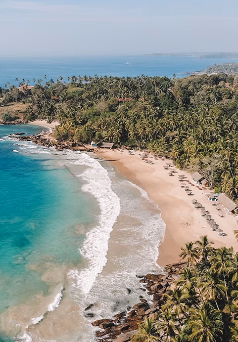 A breathtaking overhead view of a secluded tropical coastline with clear blue waters, perfect for a relaxing beach stop on a private Sri Lanka beach tour