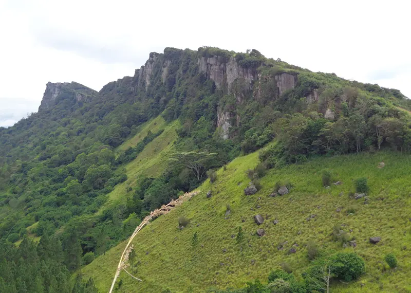 Scenic mountain hiking landscape featuring rocky cliffs and vibrant green highland hills