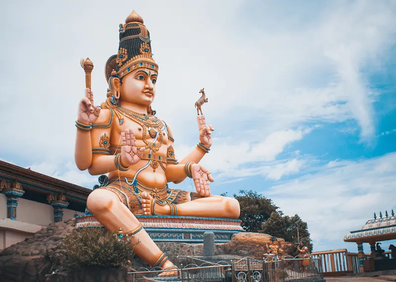 Massive and colorful Hindu deity statue seated outdoors against a bright sky