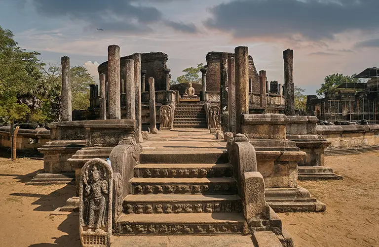 The intricately carved stone steps and pillars of the ancient Polonnaruwa Vatadage leading to a seated Buddha statue, highlighting the historical landmarks included in our Sri Lanka Ancient Echoes & Emerald Highlands package.