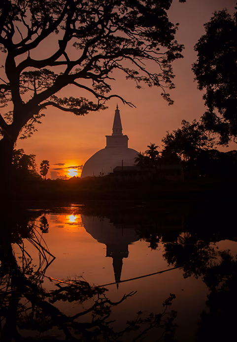 A breathtaking sunset silhouette of a massive ancient Buddhist stupa reflecting in a calm lake, a magnificent cultural highlight in our Sri Lanka itinerary packages