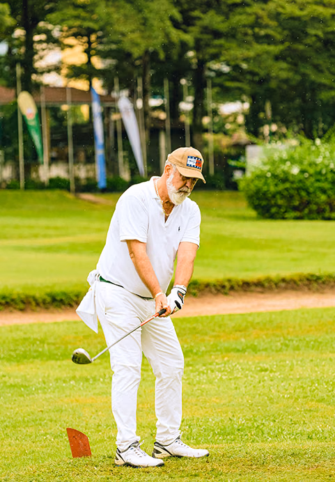 A senior golfer taking a swing on a beautiful, lush green golf course, showcasing the high-quality golfing experiences available in Sri Lanka