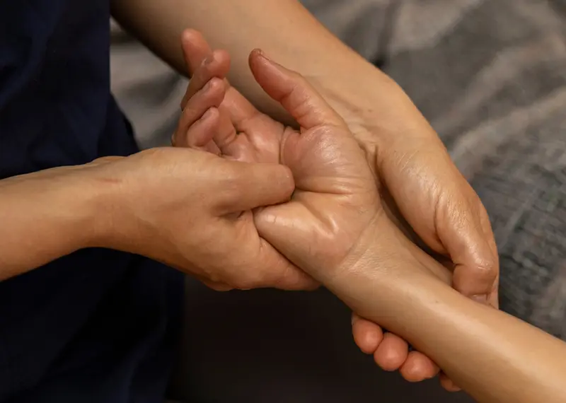 A professional therapist massages a client's oiled hand during an Ayurvedic treatment