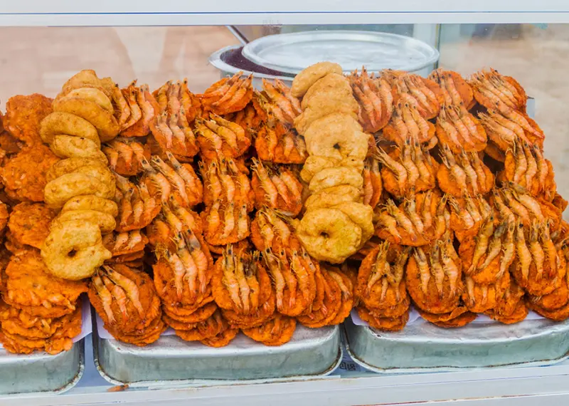 Crispy fried lentil fritters topped with whole prawns at a street market