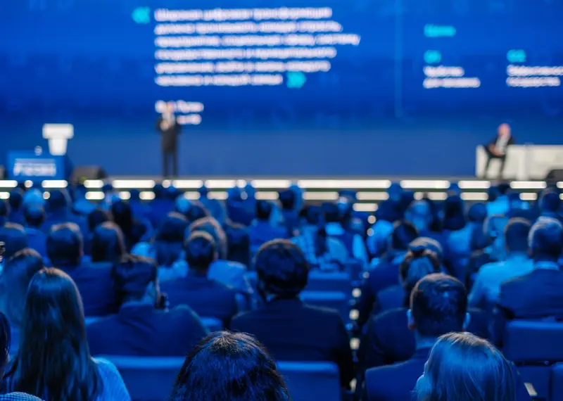 Audience listening to a keynote speaker during a large business corporate conference