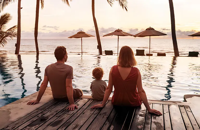 A family relaxing by an infinity pool looking out at a tropical beach sunset, highlighting the family-friendly resorts included in our Sri Lanka family tour packages