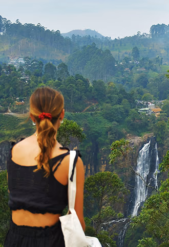 A woman enjoying a peaceful view of a misty mountain valley and distant waterfall during a custom Sri Lanka tour through the highlands