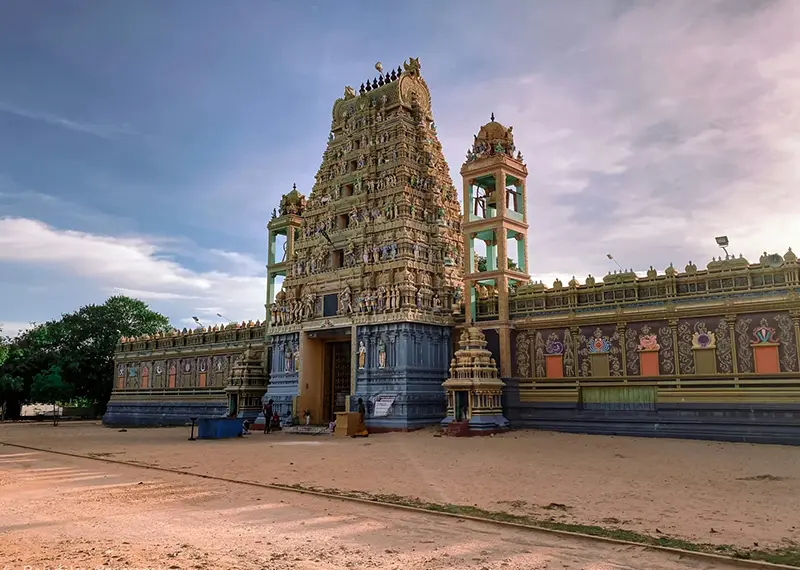 An ornate Hindu temple with detailed sculptures stands under a clear sky