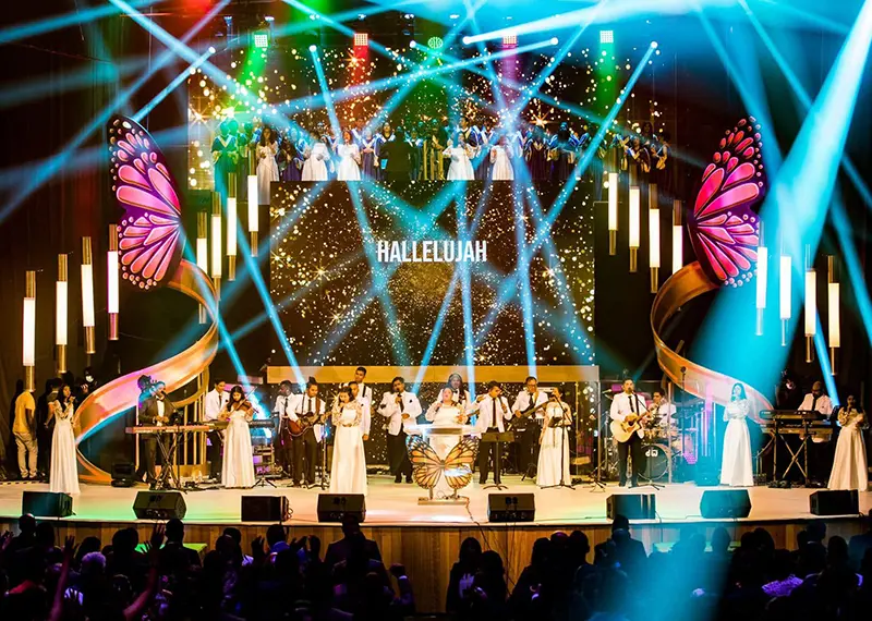 A vibrant stage filled with performers under colorful lights singing worship music