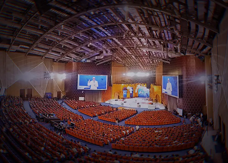 A massive indoor convention center auditorium filled with audience for an event