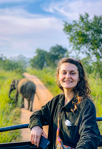A happy woman safely observing a wild elephant from a safari vehicle, showcasing the thrilling wildlife adventures available on our Sri Lanka tours