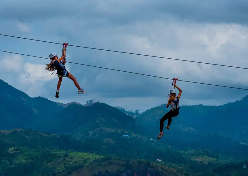 Excited tourists gliding on a mega zipline across beautiful Sri Lankan mountains