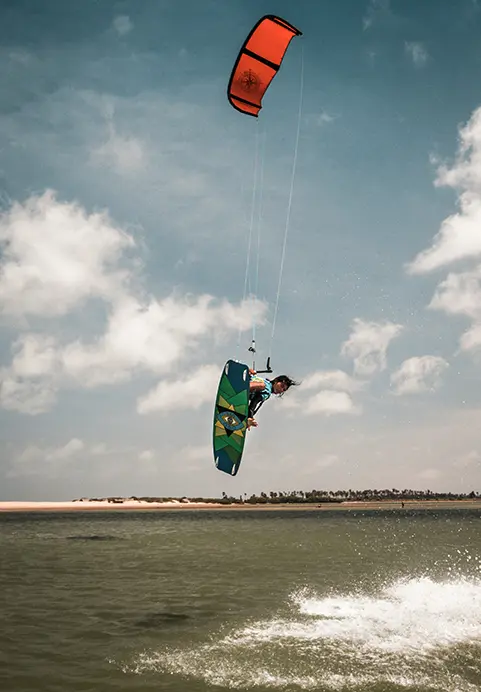 A kiteboarder performing a high jump over a flat water lagoon, showcasing the thrilling water sports adventures included in our Sri Lanka Sunrise Shores - The Ultimate Coastal Odyssey package.