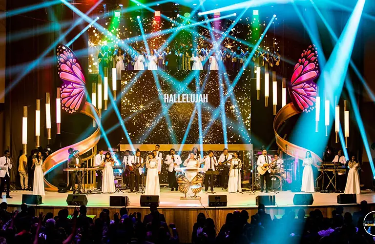 A vibrant illuminated stage filled with musical performers under bright colorful lights included in The Grand Miracle Dome & Island Odyssey package
