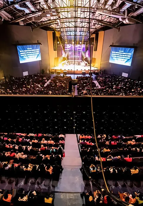 High angle vertical view of a large crowd inside an auditorium hall included in The Grand Miracle Dome & Island Odyssey package