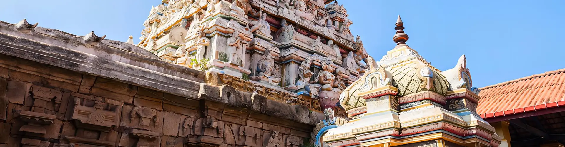 An ancient Hindu temple featuring an intricately carved stone gopuram covered in detailed statues against a clear blue sky, a fascinating cultural site to explore on our The Ramayana Trail tour
