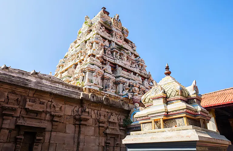 An ancient Hindu temple featuring an intricately carved stone gopuram covered in detailed statues against a clear blue sky, a fascinating cultural site to explore on our The Ramayana Trail tour
