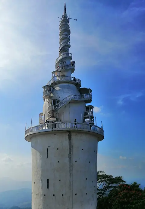 The unique spiraling architecture of the white Ambuluwawa Tower reaching into a bright blue sky, a thrilling viewpoint and cultural site often featured in our The Ultimate Family Escapade tour