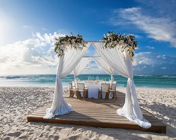 A beautiful white draped canopy with floral arrangements set up for a romantic beach wedding, showcasing the specialized event planning services included in our Sri Lanka itinerary packages