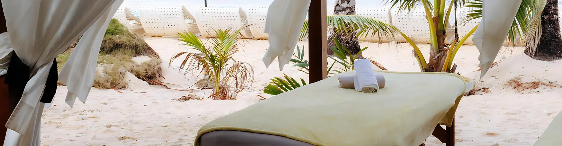 A relaxing outdoor massage table set up on a tropical white sand beach, an idyllic wellness experience to included in Wander & Awaken - The 11 Day Nervous System Reset package